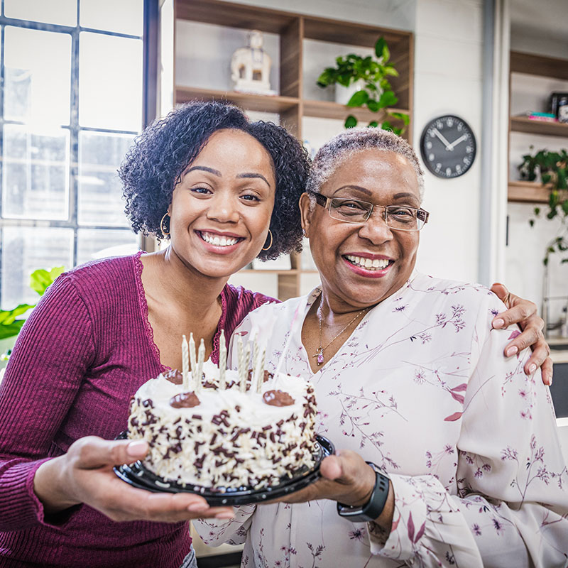 Two women holding a birthday cake